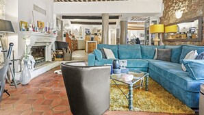 Un salon avec un canapé d’angle, une cheminée et un mur en pierre.