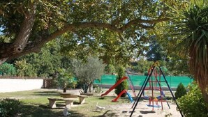 A playground with swings and slides, surrounded by trees and a green fence. - Casa Rural El Manantial near Ciudad Rodrigo with Private Pool and Mountain Views (CIUDAD RODRIGO)
