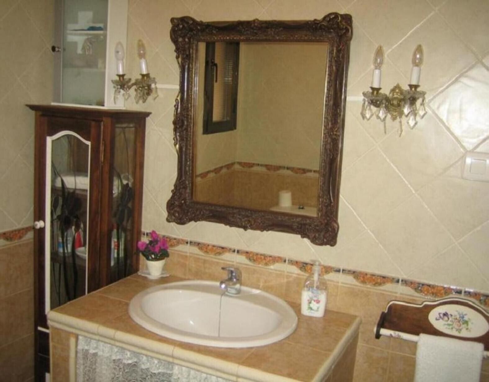 Un bany amb un mirall gran, un lavabo i un armari.