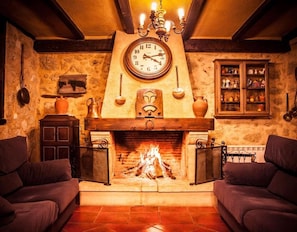 A cozy room with a fireplace, a clock, and a cabinet with decorative items.