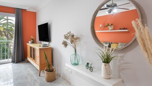 A modern living room with a television, a large mirror, and a window with a view of palm trees. - Apartment 'La Fuente' with Balcony and Wi-Fi (El Paso)