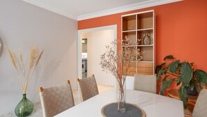 A dining area with a white table, chairs, a vase with dried plants, and a bookshelf. - Apartment 'La Fuente' with Balcony and Wi-Fi (El Paso)
