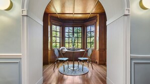 A room with a round table and four chairs, large windows, and wooden flooring. - ★ HostWise Stays ★ Charming Squirrel Hill Home with Garage, Near CMU (Pittsburgh)