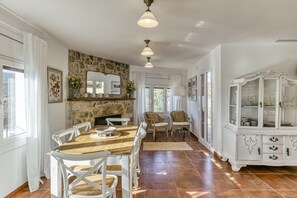 A dining area with a stone fireplace, white furniture, and a white cabinet with glass doors.