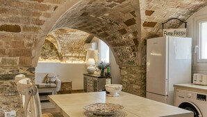 Una cocina rústica con arcos de ladrillo visto, una isla central, un refrigerador y una lavadora.