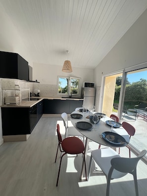 A modern kitchen with a dining area, large windows, and a view of the outdoors. - Holiday Home 'Maison Proche Vendée Globe 6p' with Private Terrace and Air Conditioning (Sainte-Foy)