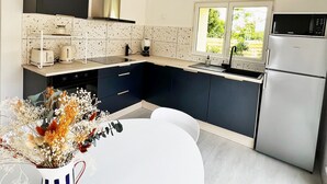 Eine moderne Küche mit weißer Decke, einer schwarz-weißen Spritzschutzwand, einem Edelstahl-Kühlschrank und einem Fenster mit Blick auf Grünflächen.