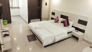 A hotel room with a large bed, bedside tables, a wardrobe, and a bathroom visible through an open door. - Raj Mahal Rooms & Banquet Hall (Patna)