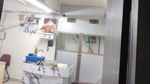 A reception area with a marble counter, a reception desk, a brown leather couch, and a sign that reads "RECEPTION". - Raj Mahal Rooms & Banquet Hall (Patna)