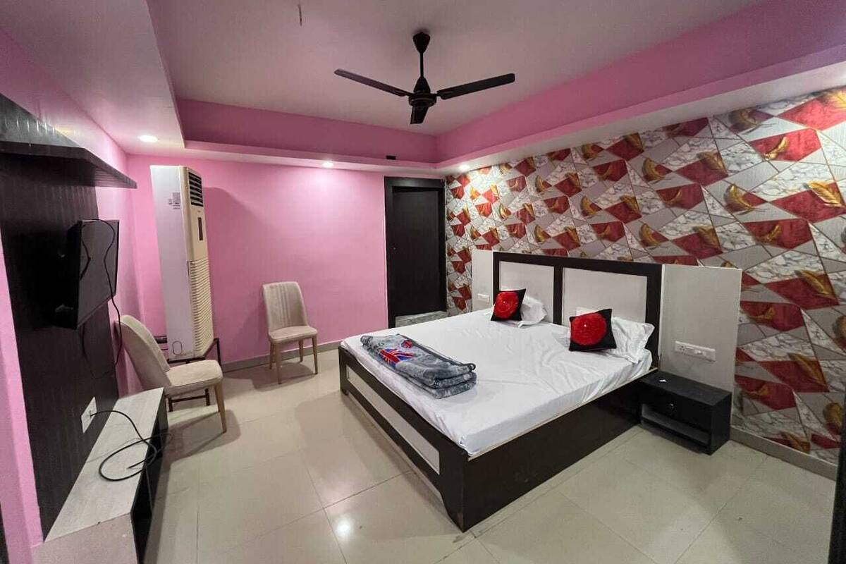 A bedroom with a bed, a chair, a desk, and a TV.