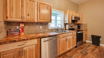 A kitchen with wooden cabinets, a dishwasher, a microwave, and a trash can.