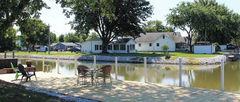 A lakeside property with a dock, chairs, and a table.