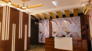 Un espace d’accueil moderne avec un mur en marbre, des éléments décoratifs en bois et des luminaires suspendus.
