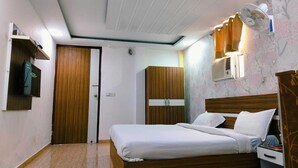 Une chambre à coucher avec un lit, une armoire, un téléviseur et un ventilateur de plafond.