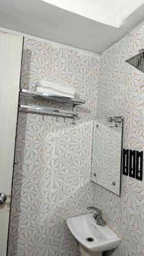 Une salle de bain avec un mur orné d’un motif géométrique, un lavabo blanc et un porte-serviettes.