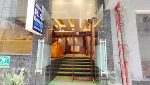 L’entrée d’un hôtel, avec un comptoir d’accueil, un escalier et une enseigne indiquant le nom de l’hôtel et son statut (hôtel de passage ou résidence).