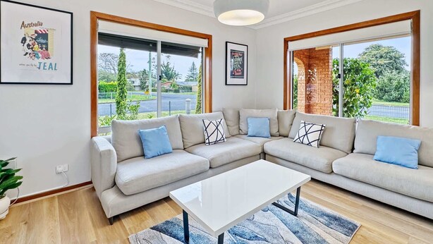 Ein modernes Wohnzimmer mit einem Ecksofa, einem Couchtisch und großen Fenstern mit Blick ins Freie.