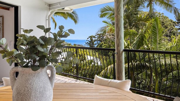 Ein Balkon mit Blick auf das Meer, einer Topfpflanze und einem Holzdeck.