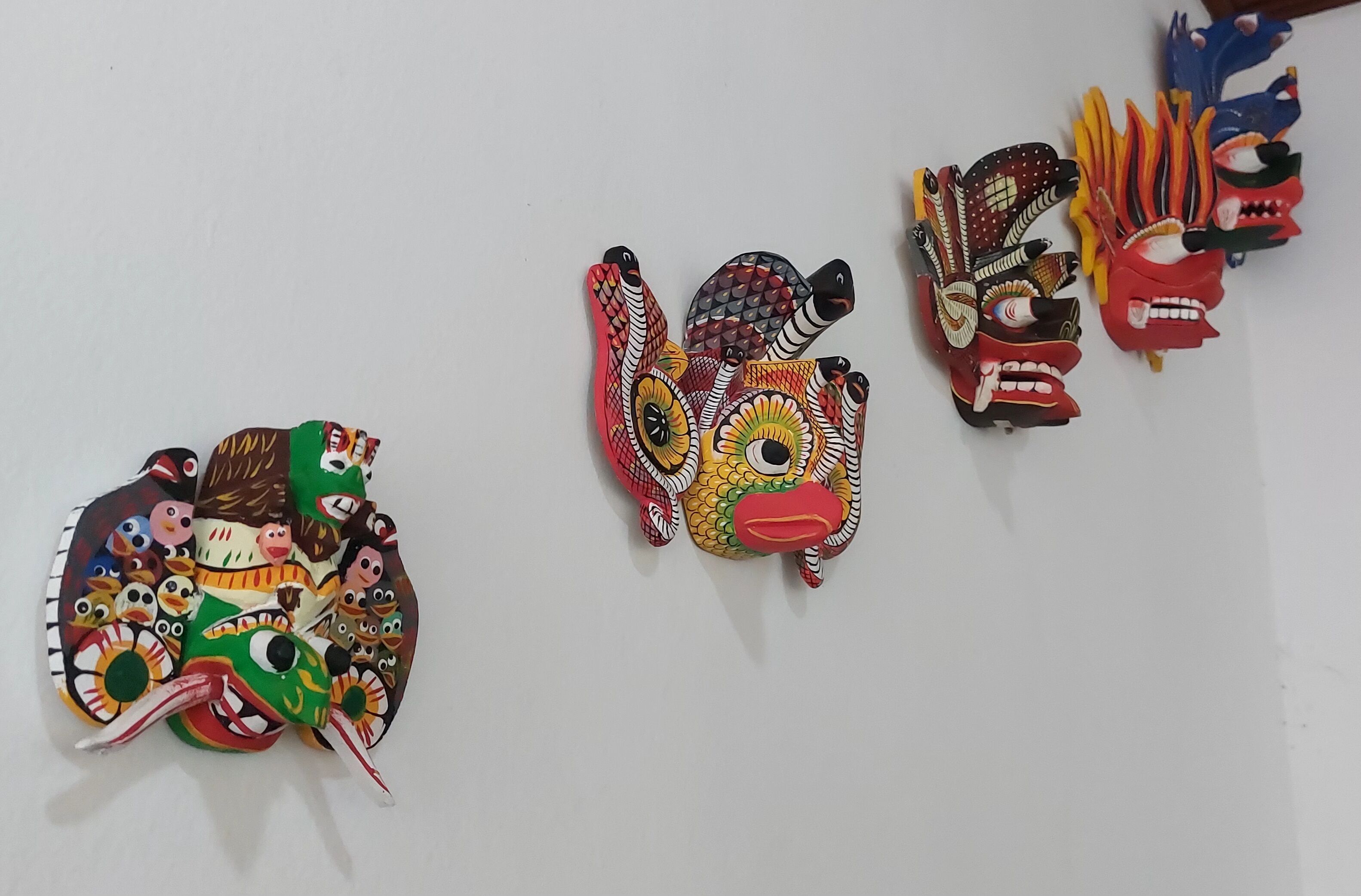 A collection of colorful masks on a white wall.