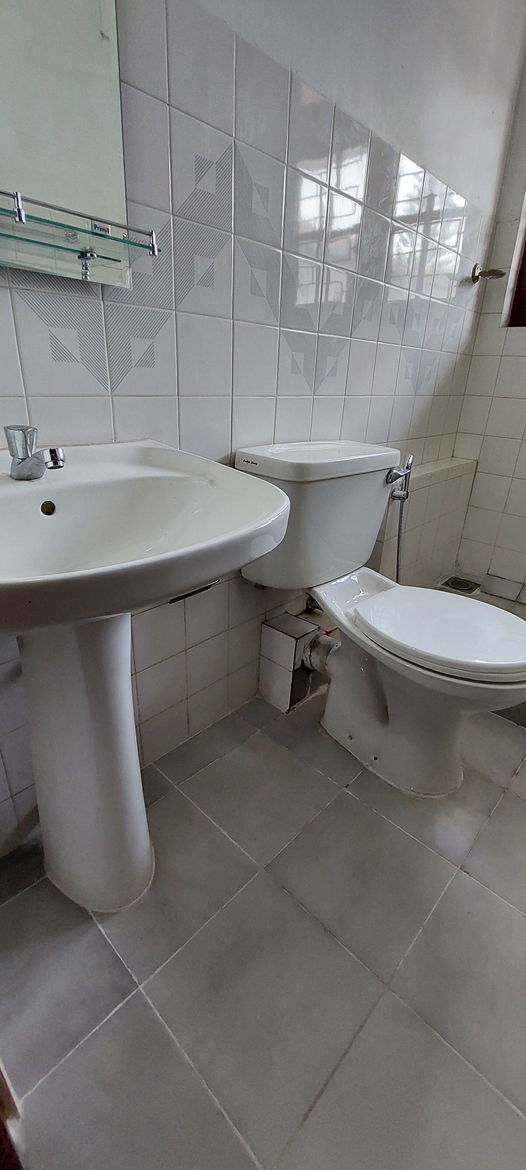 A bathroom with two white sinks and a toilet, tiled floor, and a mirror above the sink.