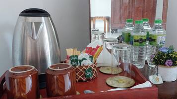 A tray with a coffee maker, jars, bottled water, and a small potted plant.