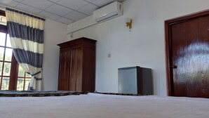 Una habitación de hotel con un ventanal grande, un armario, un equipo de aire acondicionado y una puerta.