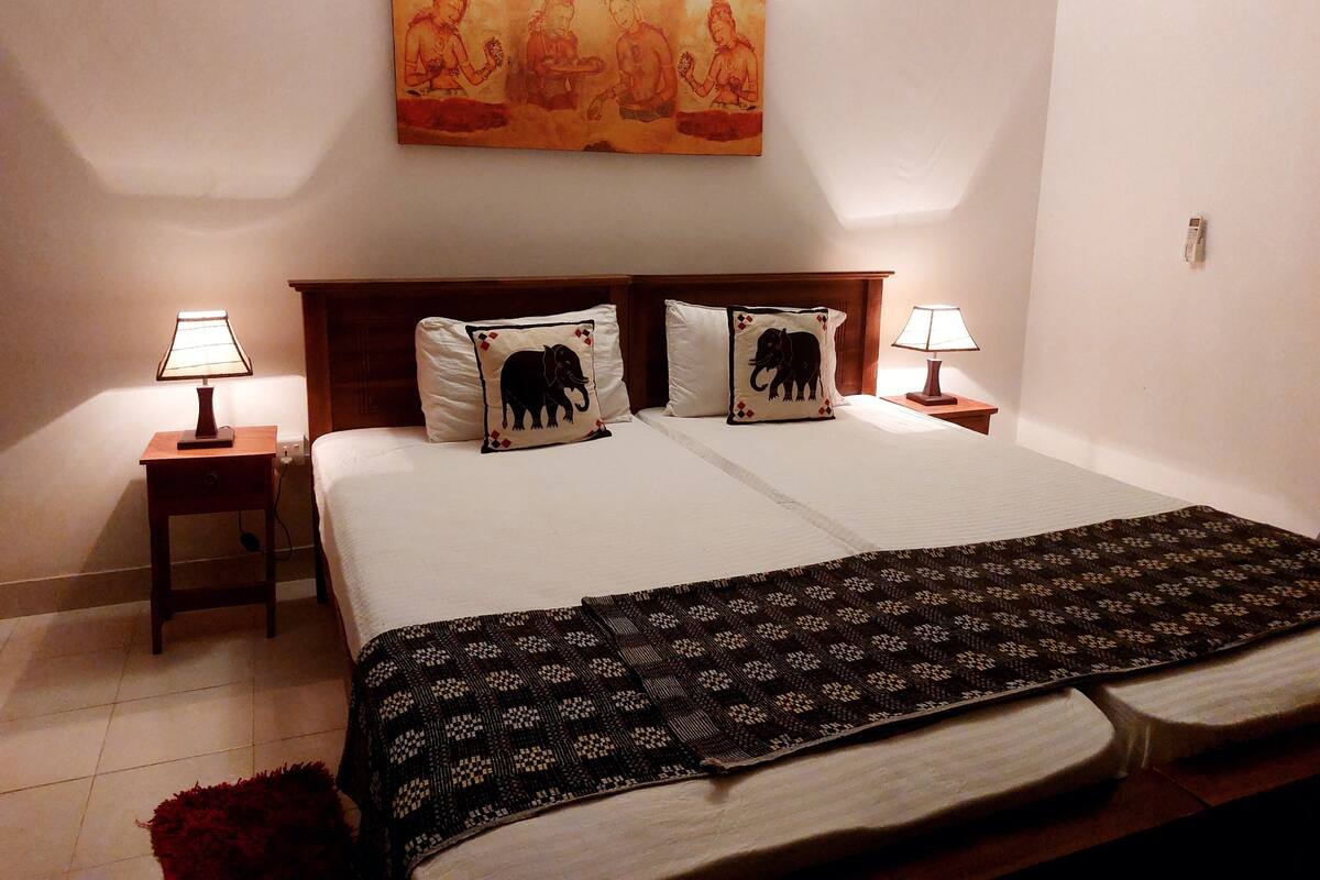 A hotel room with a large bed, two nightstands, two lamps, and a painting above the bed.