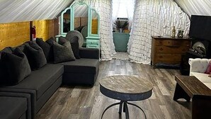 Une pièce mansardée chaleureuse avec un plafond en bois, un canapé, une petite table ronde et une commode.