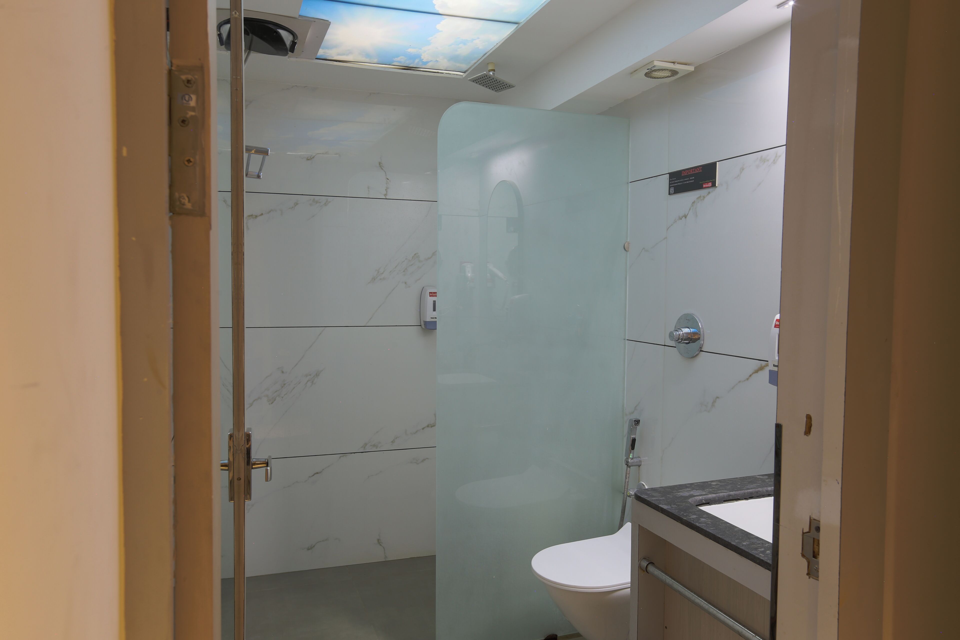 A bathroom with a glass partition, a toilet, a sink, and a shower.