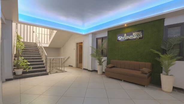 A hotel lobby with a staircase, a sofa, and a sign that reads 'Hotel Shrimmaya.' - Hotel Shrimmaya (Ujjain)