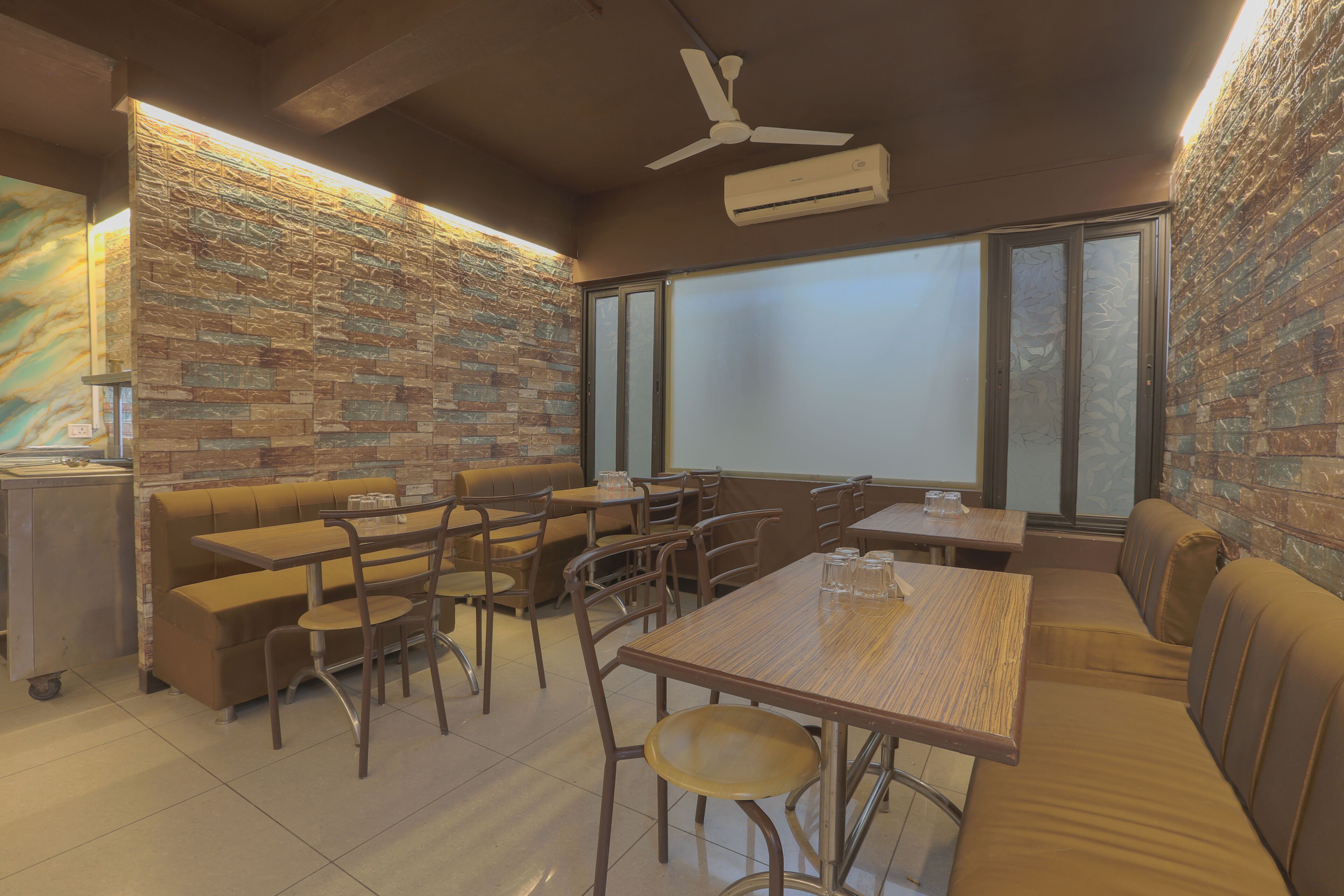 A restaurant with brick walls, wooden furniture, and a ceiling fan.