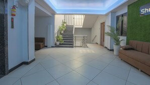 A modern interior with a staircase, a reception area, and a green wall. - Hotel Shrimmaya (Ujjain)