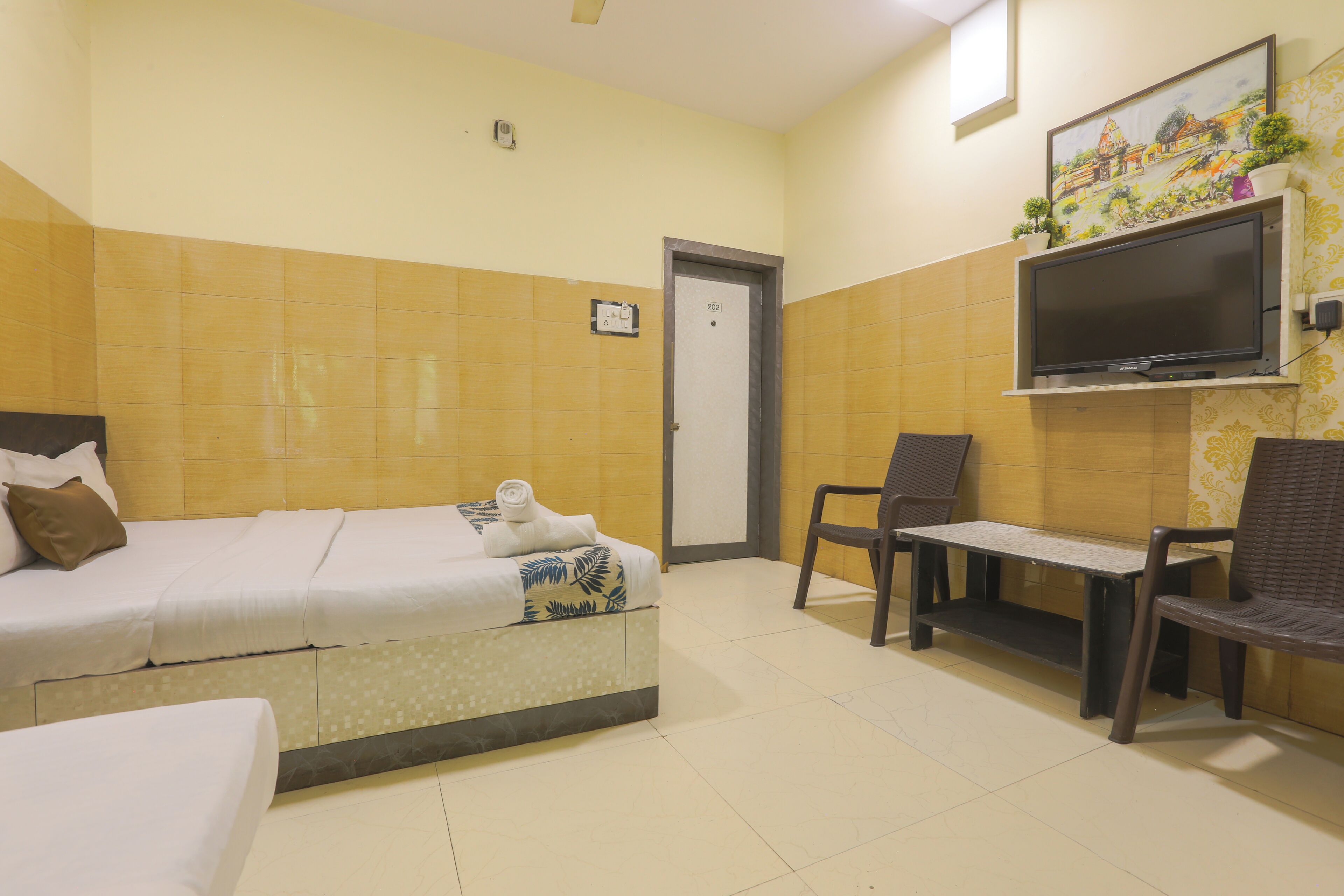 A hotel room with two beds, a TV, a small table, and a chair.