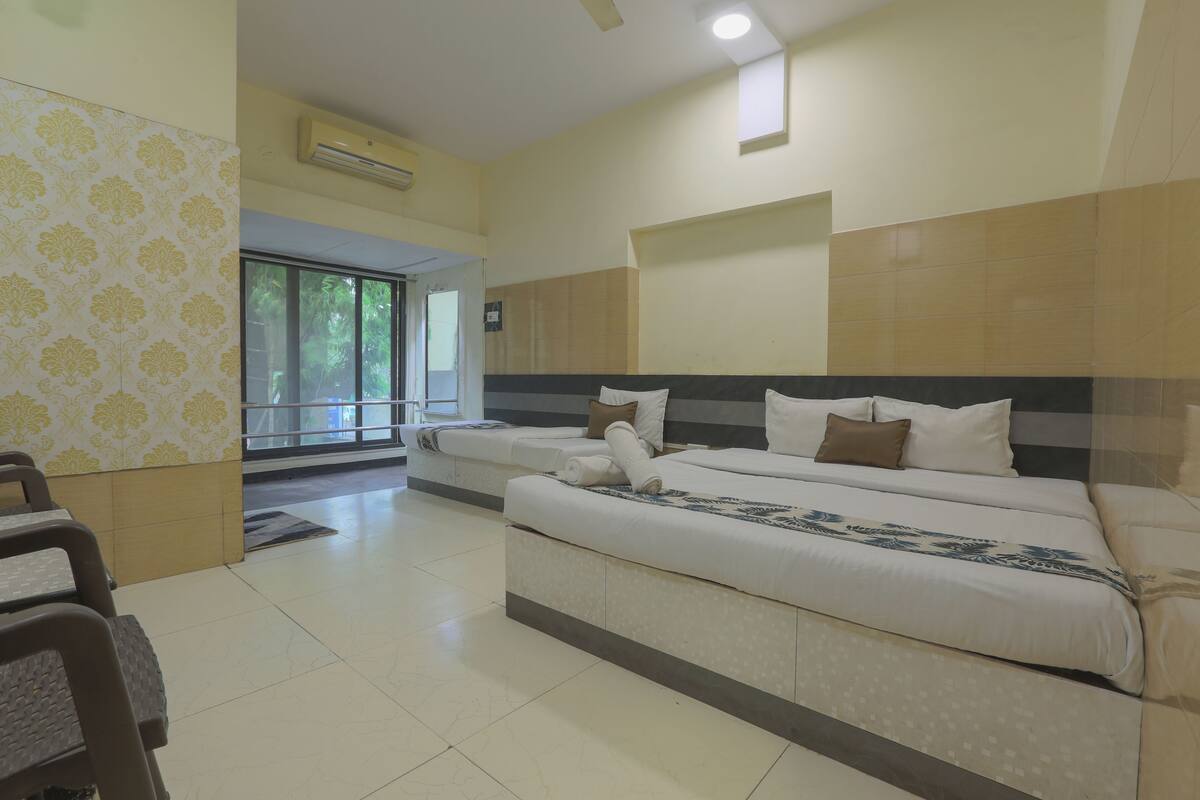 A hotel room with a large bed, a window, a door leading outside, and a small table.