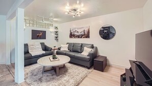 Un salon moderne avec un canapé gris, une table basse ronde et un meuble pour la télévision.