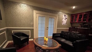 A living room with a glass coffee table, two black leather sofas, a wooden floor, and a door with a glass panel. - Upstairs bar, palapa, 5 bedroom, king suite, Gig WiFi, great location  (Eagle Pass)