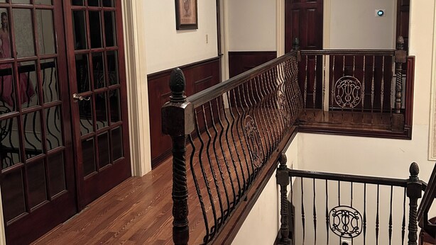 A wooden staircase with a black railing, white walls, and a framed picture on the wall. - Upstairs bar, palapa, 5 bedroom, king suite, Gig WiFi, great location  (Eagle Pass)