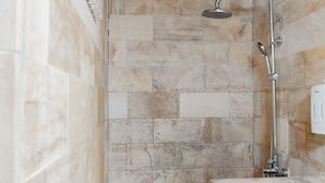 A shower area with a tiled wall and a handheld showerhead. - Bellewood Villa (Gili Trawangan)