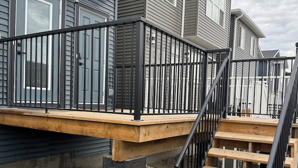 Eine Terrassenanlage eines Wohnhauses mit einer Holztreppe und schwarzen Geländern.