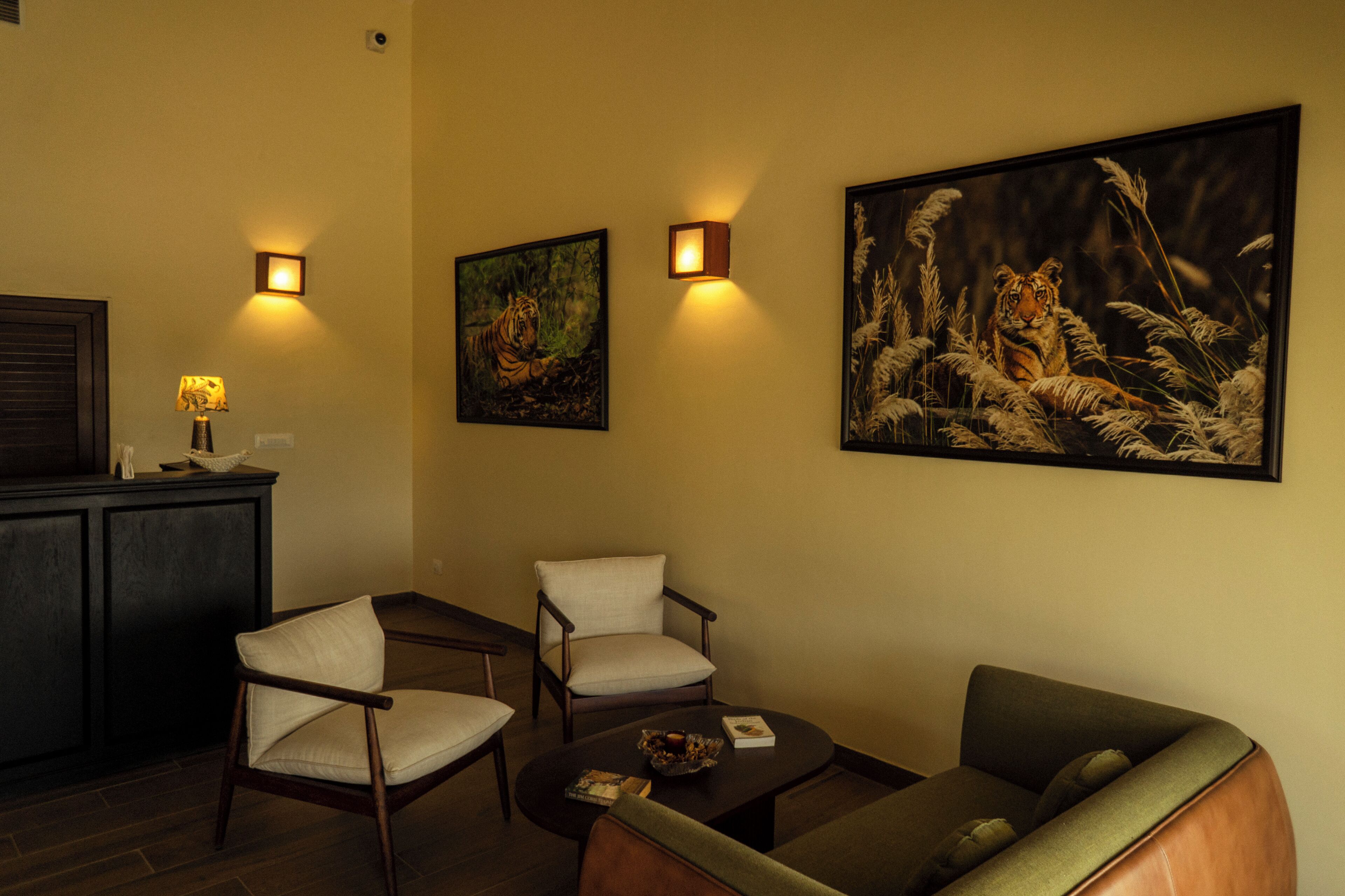 Una habitación con sofá, dos sillones, una mesita de centro y obras de arte colgadas en la pared.
