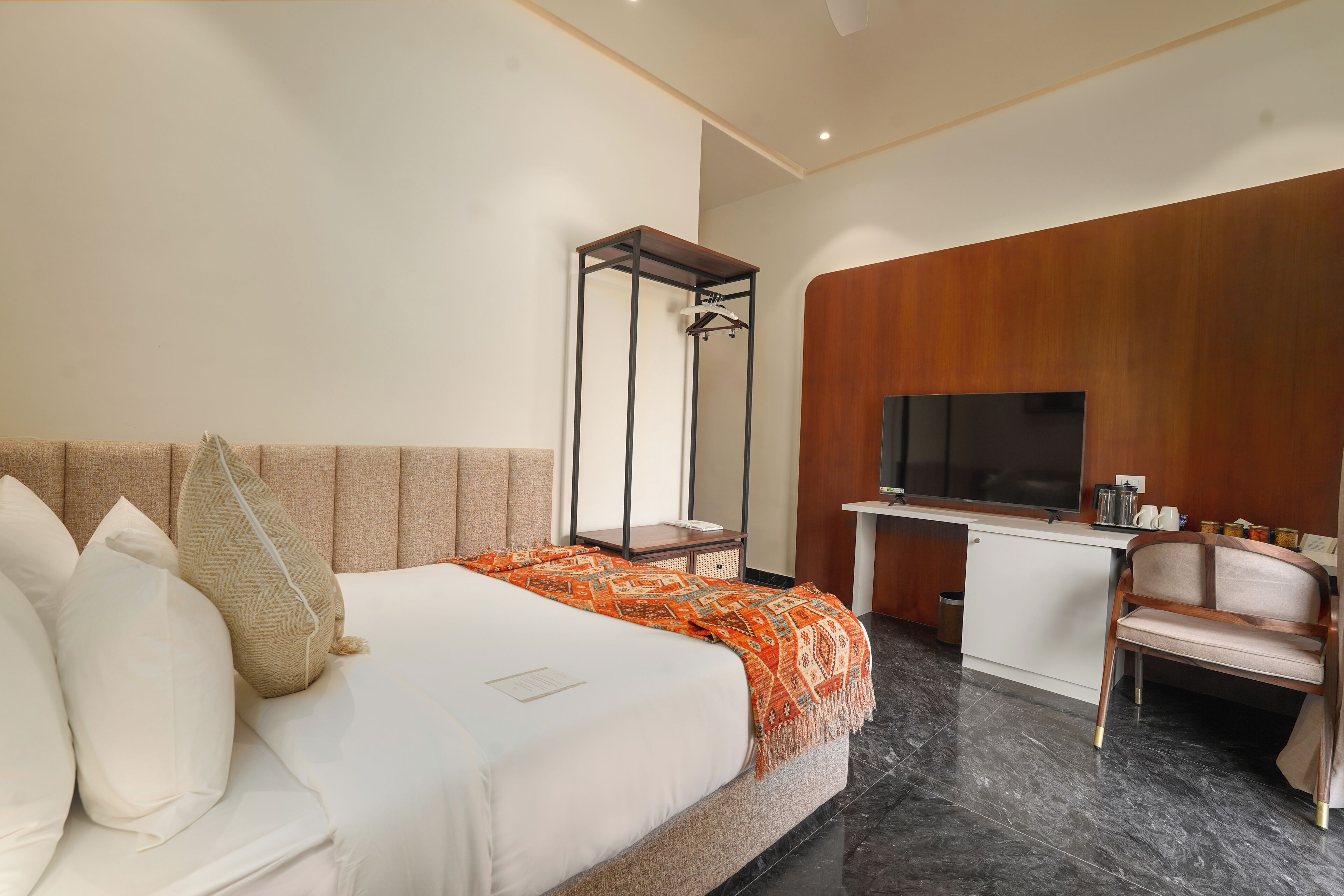 A hotel room with a bed, a desk, a TV, and a chair.
