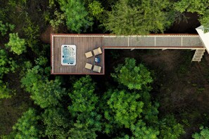 An aerial view of a wooden deck with a hot tub and seating area surrounded by dense greenery. - Tree of Life Ramvilas Bandhavgarh (Manpur)