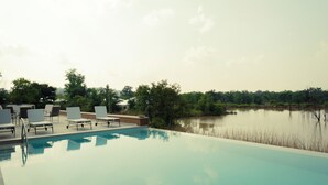 A pool area with lounge chairs and a view of a lake.