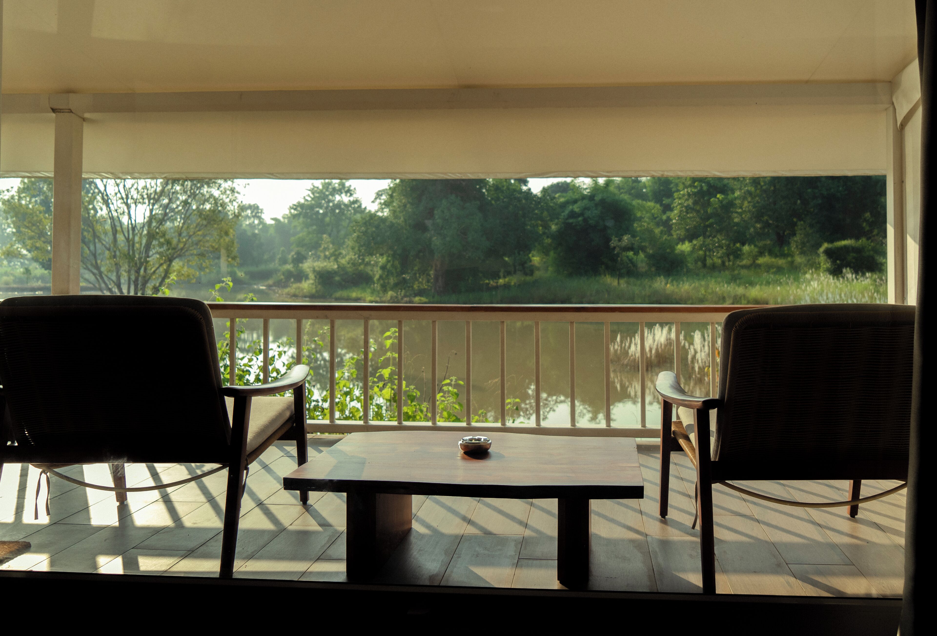 A balcony with a table and two chairs, overlooking a natural landscape.