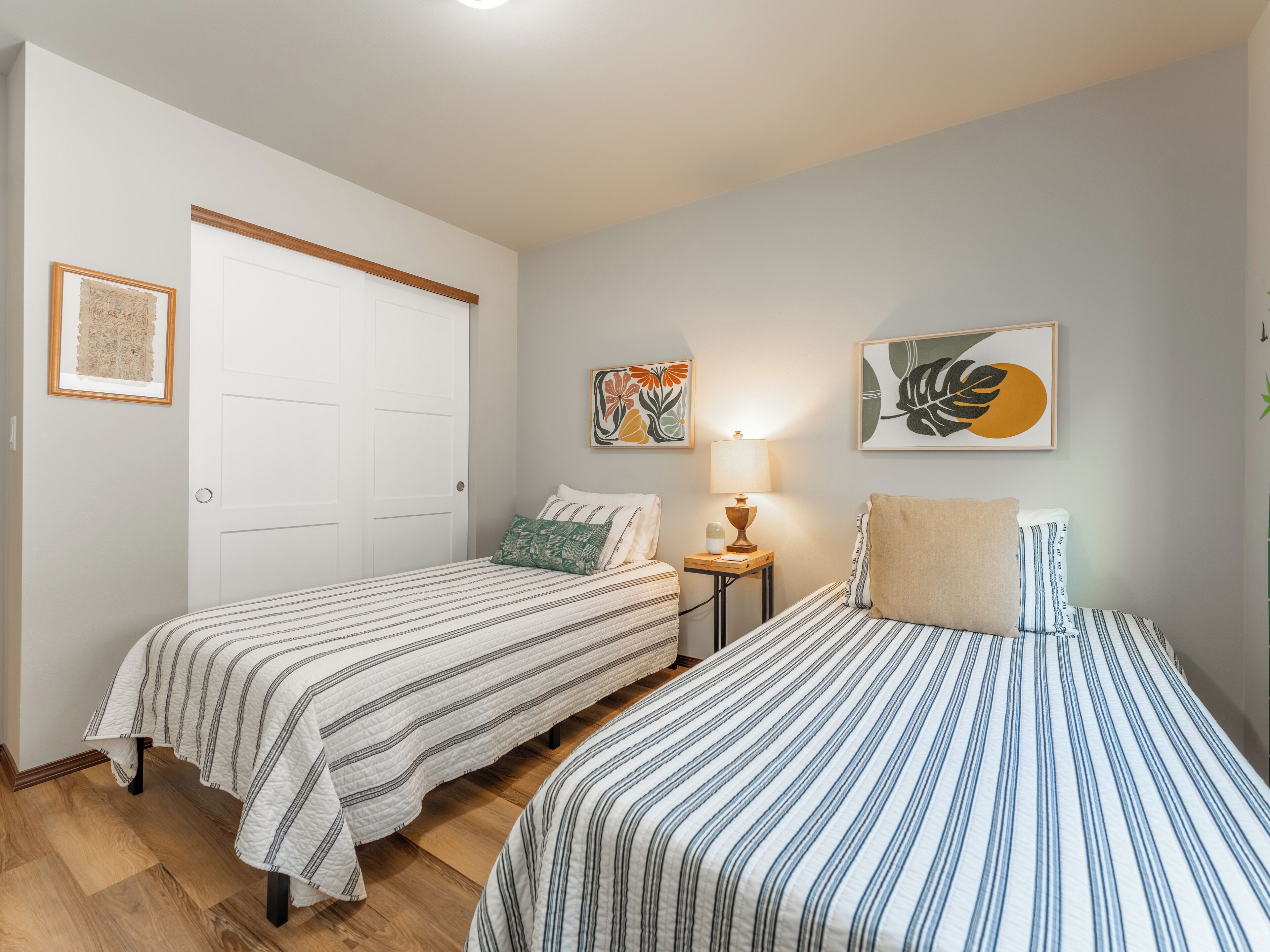 A bedroom with two beds, a nightstand, and a door.