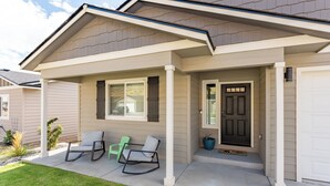 A residential house with a covered porch, a front door, and two chairs. - Hendrix Hideaway on Rock Island Golf Course! (Rock Island)