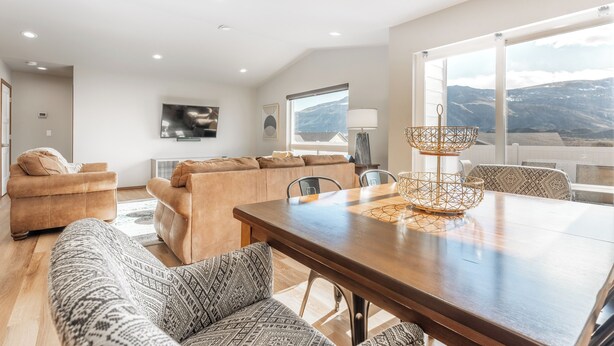 A spacious living area with a large wooden dining table, comfortable seating, and a view of mountains through large windows. - Hendrix Hideaway on Rock Island Golf Course! (Rock Island)