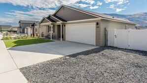 A modern two-story house with a covered garage, a well-maintained lawn, and a mountain backdrop. - Hendrix Hideaway on Rock Island Golf Course! (Rock Island)