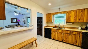 A modern kitchen with wooden cabinets, a built-in oven, and a window with a view. - Travelers Palm Beachy Paradise (Edgewater)