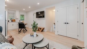 A modern living room with a dining area, a TV mounted on the wall, and a large wardrobe. - Stylish 1BD Steps from Downtown (Kitchener)